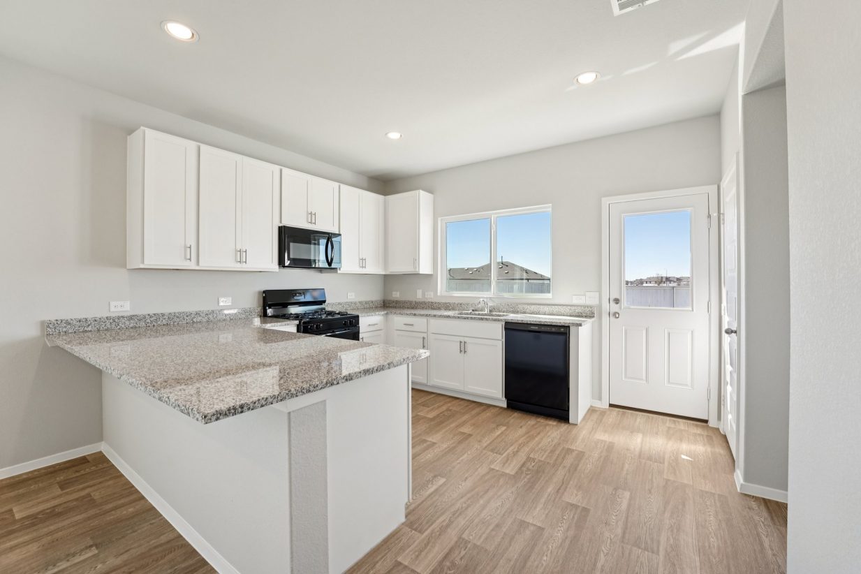 Image of a U-shaped kitchen with granite countertops, white cabinets, black appliances and a window above the sink