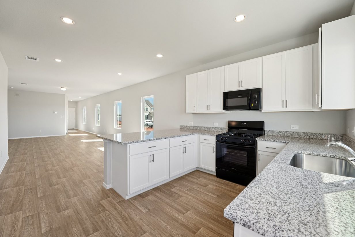 Image of a U-shaped kitchen with white cabinets, black appliaces, and granite countertops