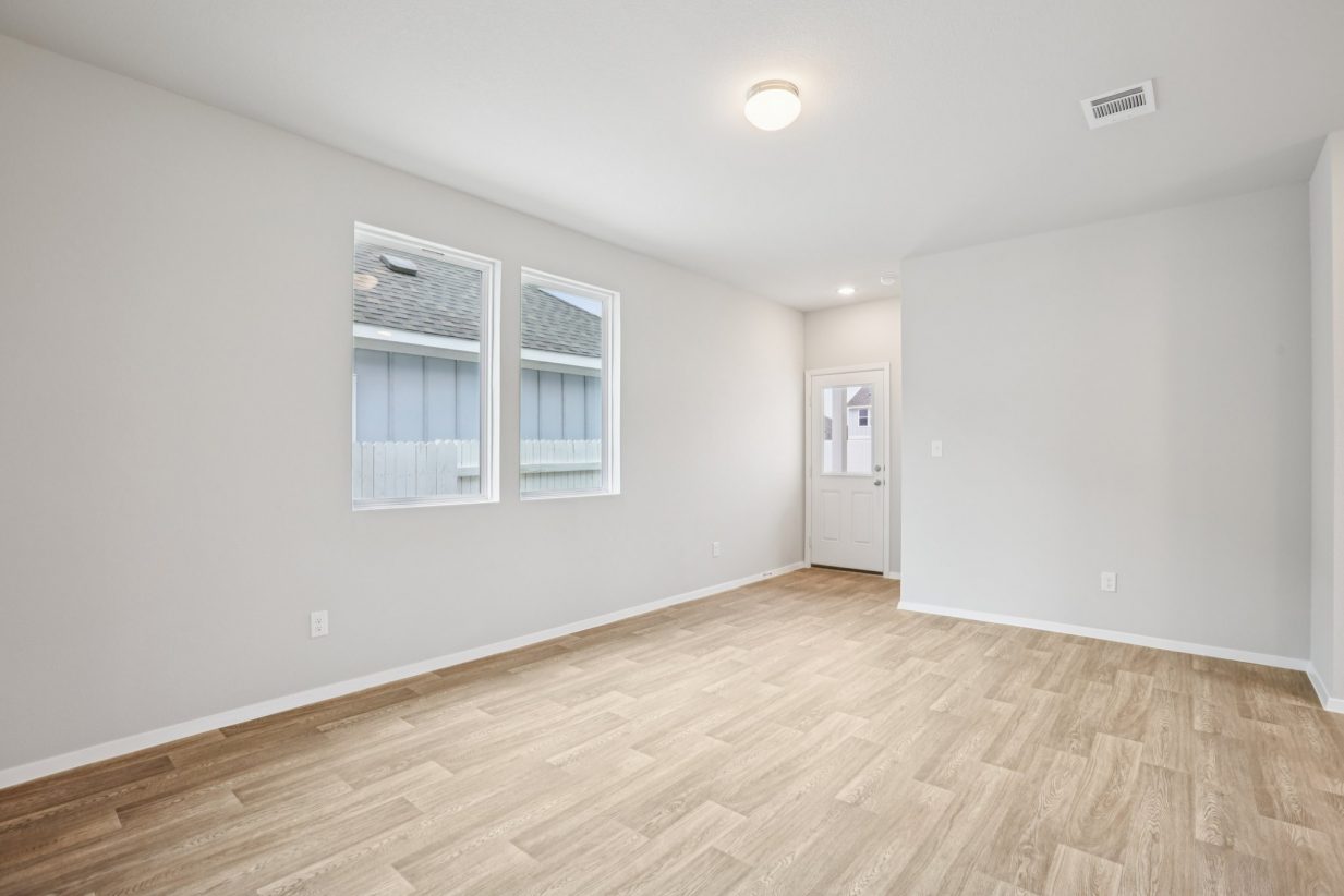 Image of a dining room area with light grey walls, vinyl flooring, two windows and a white back door