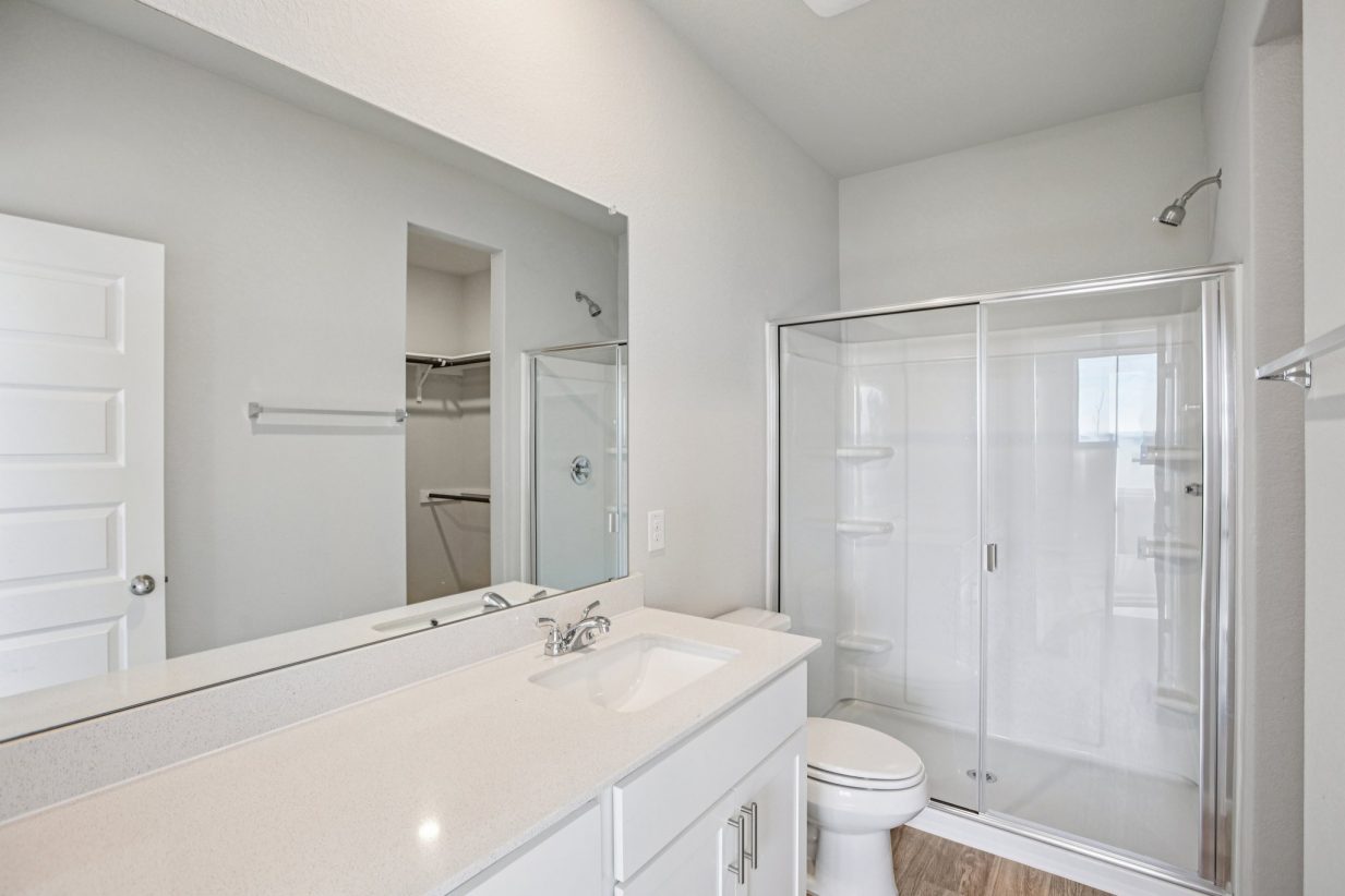 Image of a bathroom with a white dual vanity, a large mirror and a walk-in shower