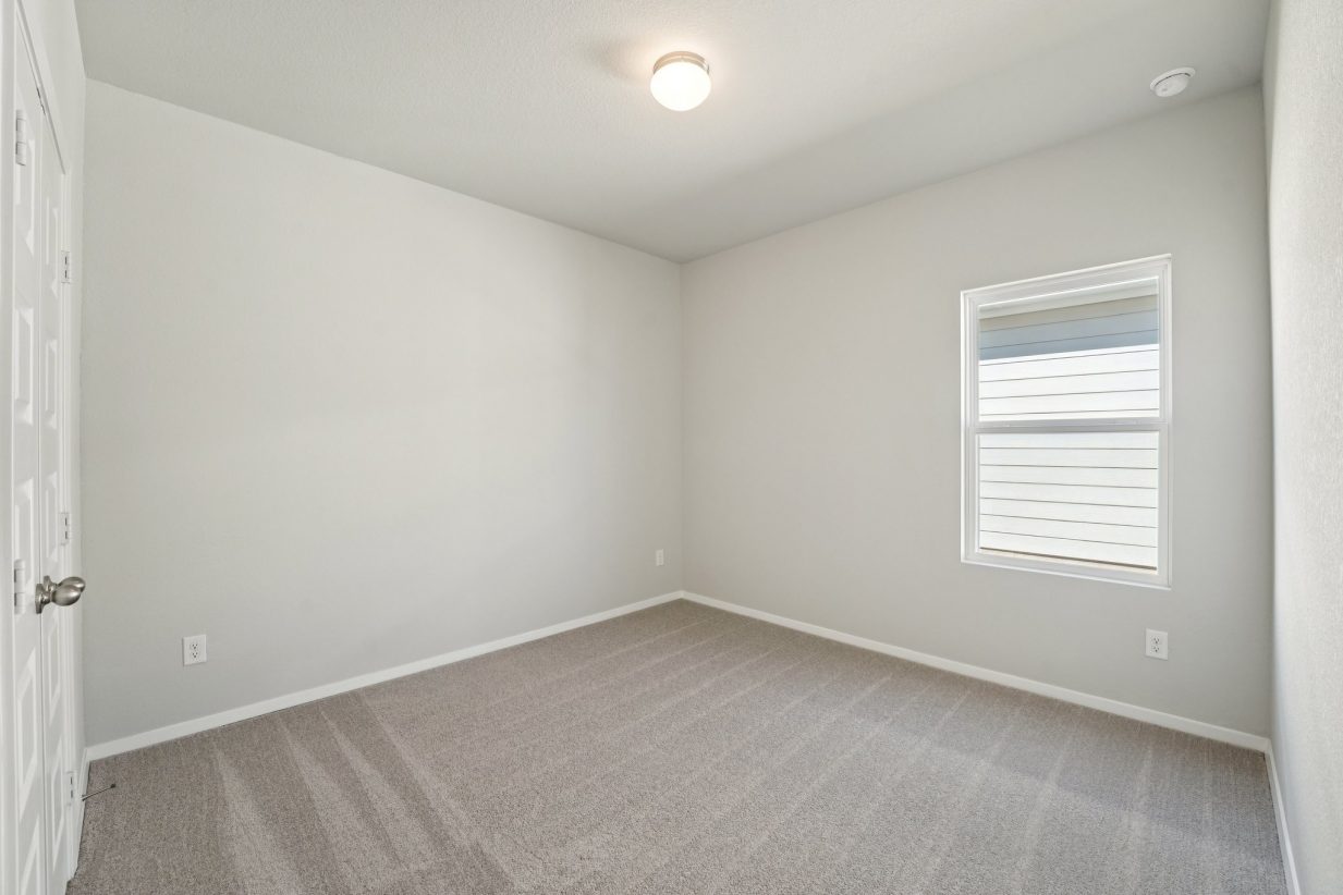 Image of a bedroom with grey walls, tan carpeting and a window with white trim