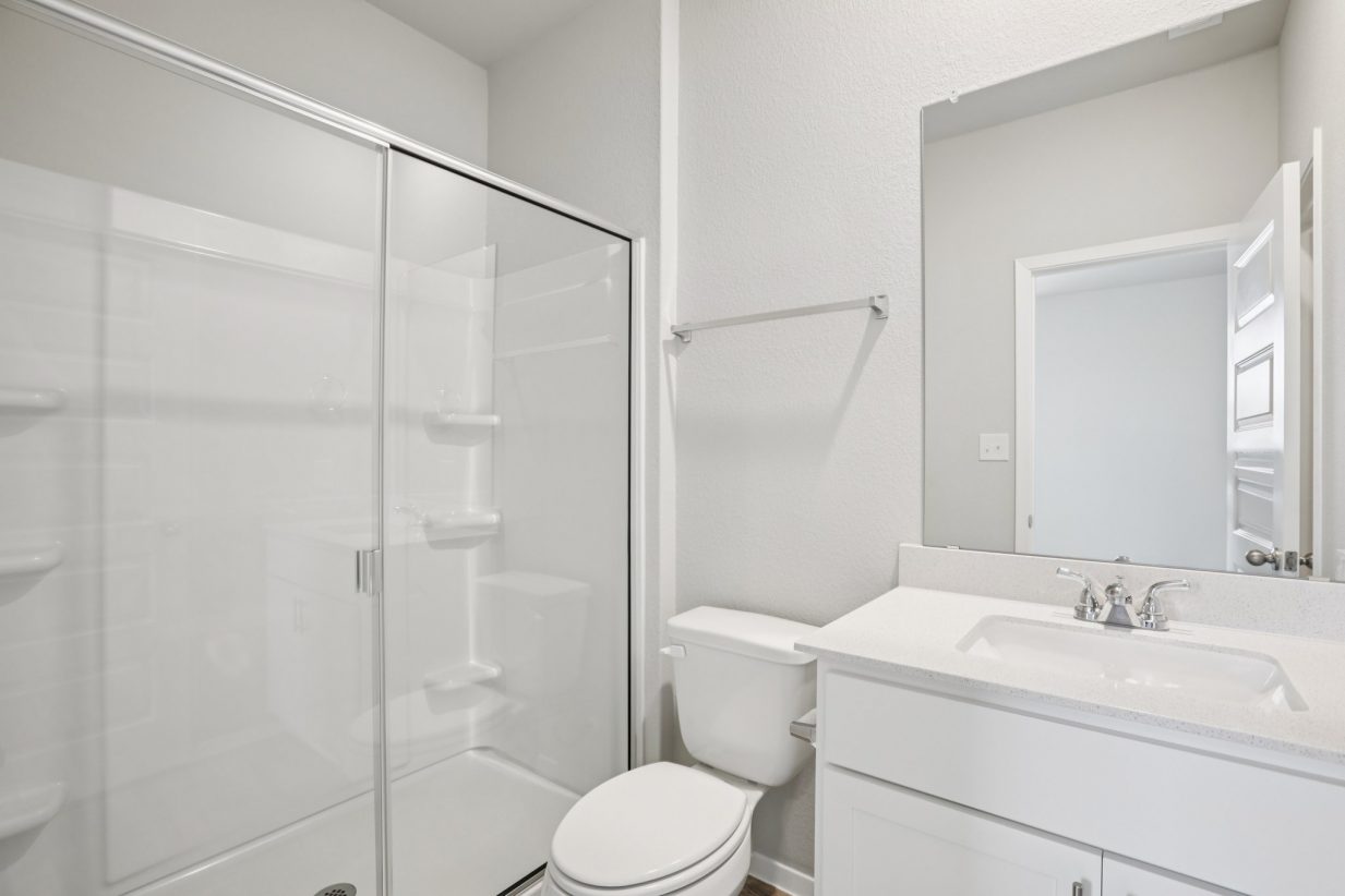 Image of a primary bathroom with white cabinets and vanity, a mirror and a walk-in shower