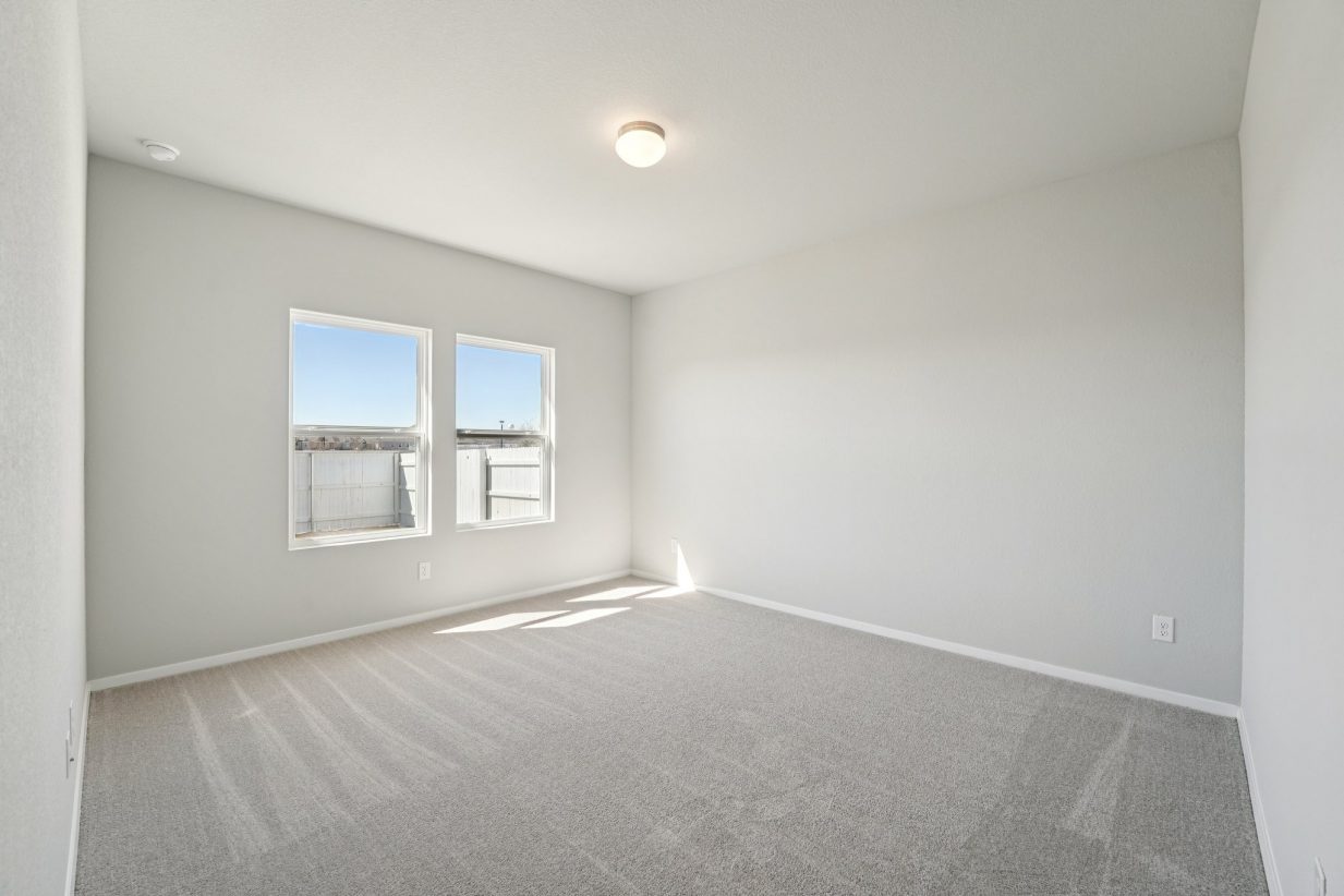 Image of a primary bedroom with grey walls, tan carpeting, windows and white trim