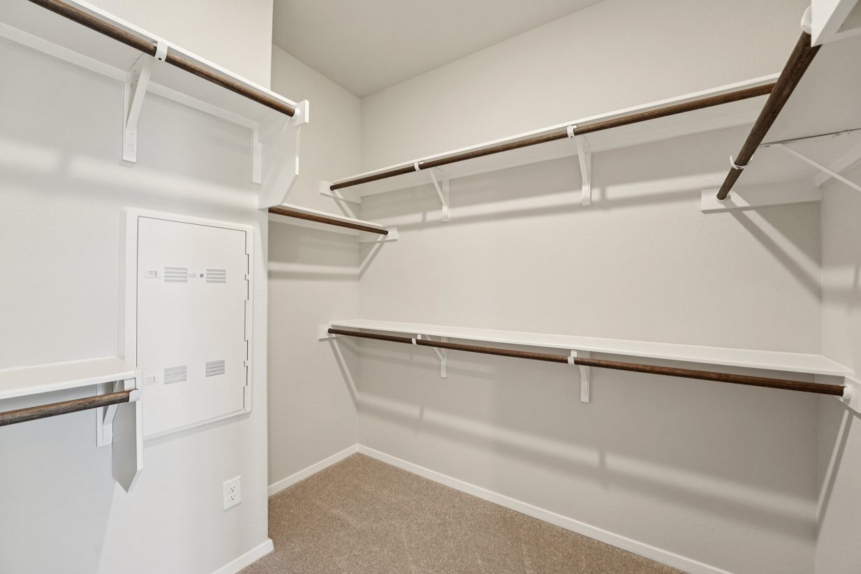 Image of a walk-in closet with white shelves and wooden rods