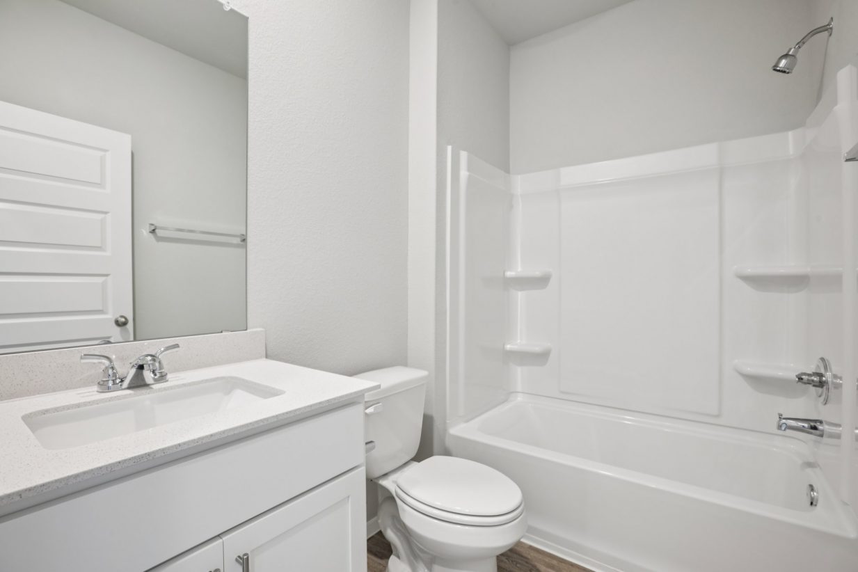 Image of a bathroom with white cabinets, vanity, a mirror, and a shower with a tub