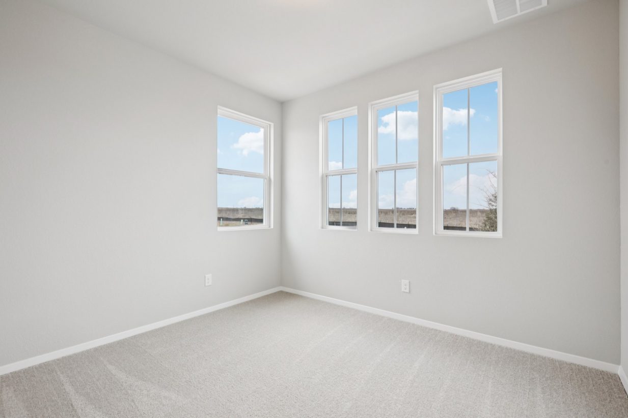 Image of a bedroom with light grey walls, tan carpeting, windows and white trim
