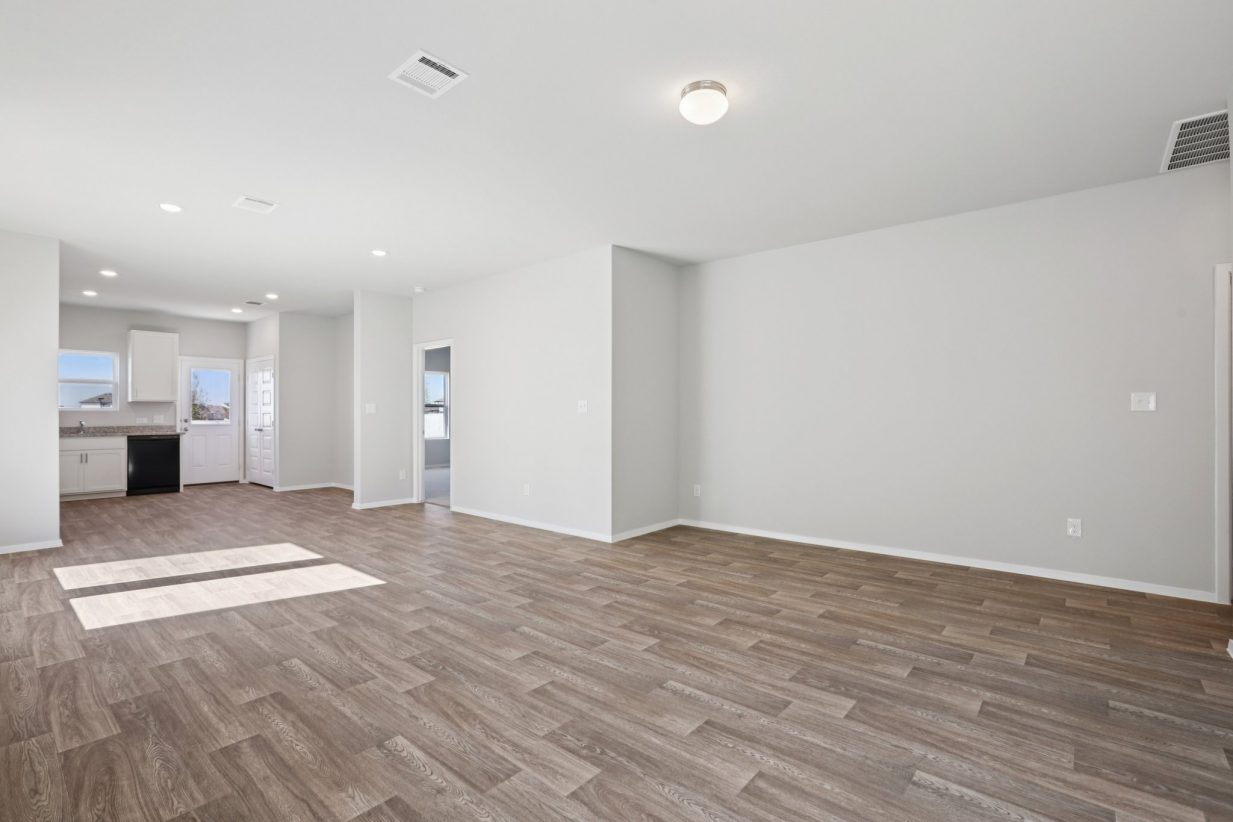 Image of a living room area with brown vinyl flooring, light grey walls, and white trim