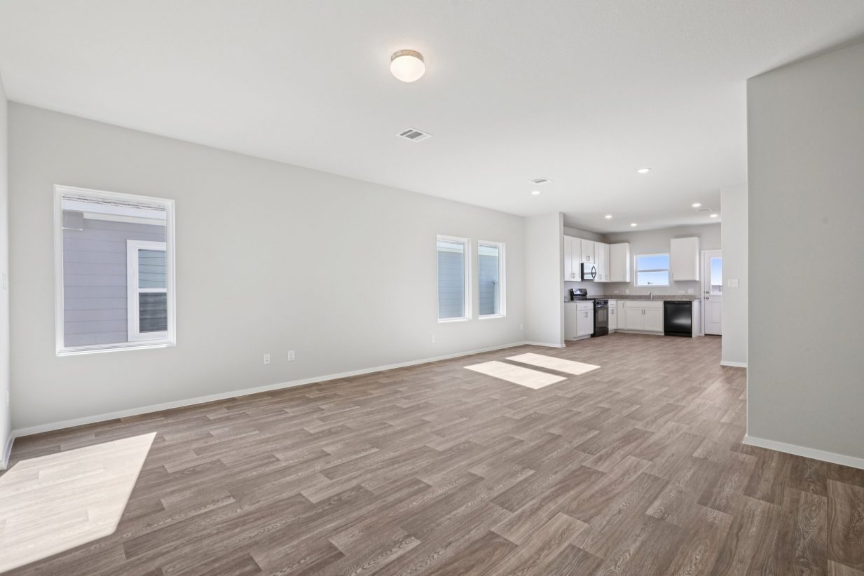 Image of a living room area with brown vinyl flooring, grey walls, and windows with white trim