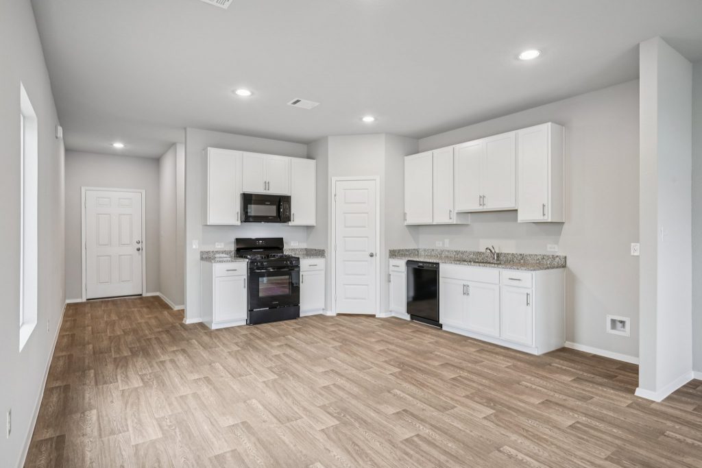 Image of a kitchen with white cabinets, black appliances, and a corner pantry