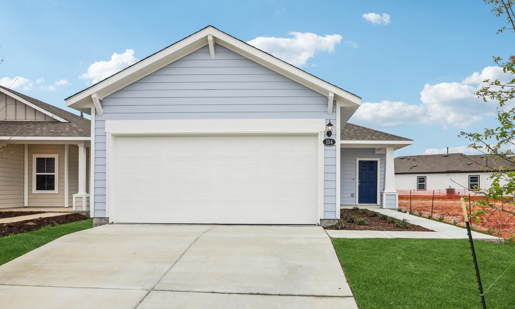 Image of a blue one story house with a cement drive way and green grass in the front yard