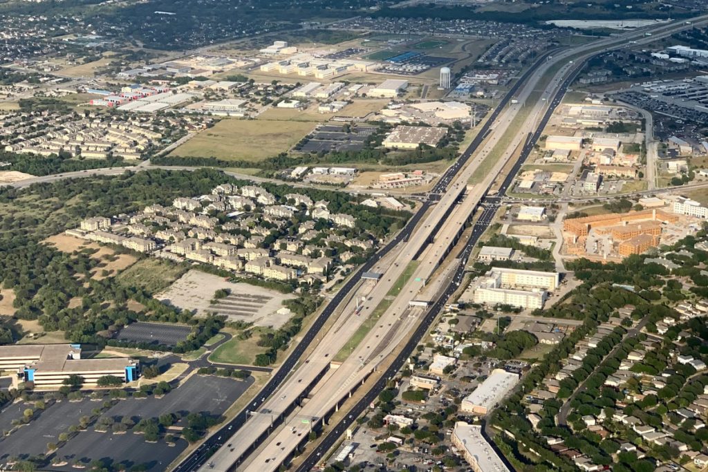 An aerial image of the city of Hutto, Texas featuring major roads, building, houses, and greenery.