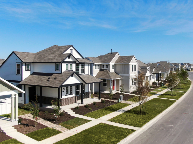 A image of neighborhood showing two story houses and single story house with green grass, street