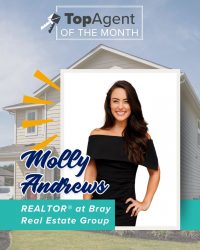 A graphic of a woman with a black dress with a white frame with a background of yellow house and the words "TopAgent of the Month".